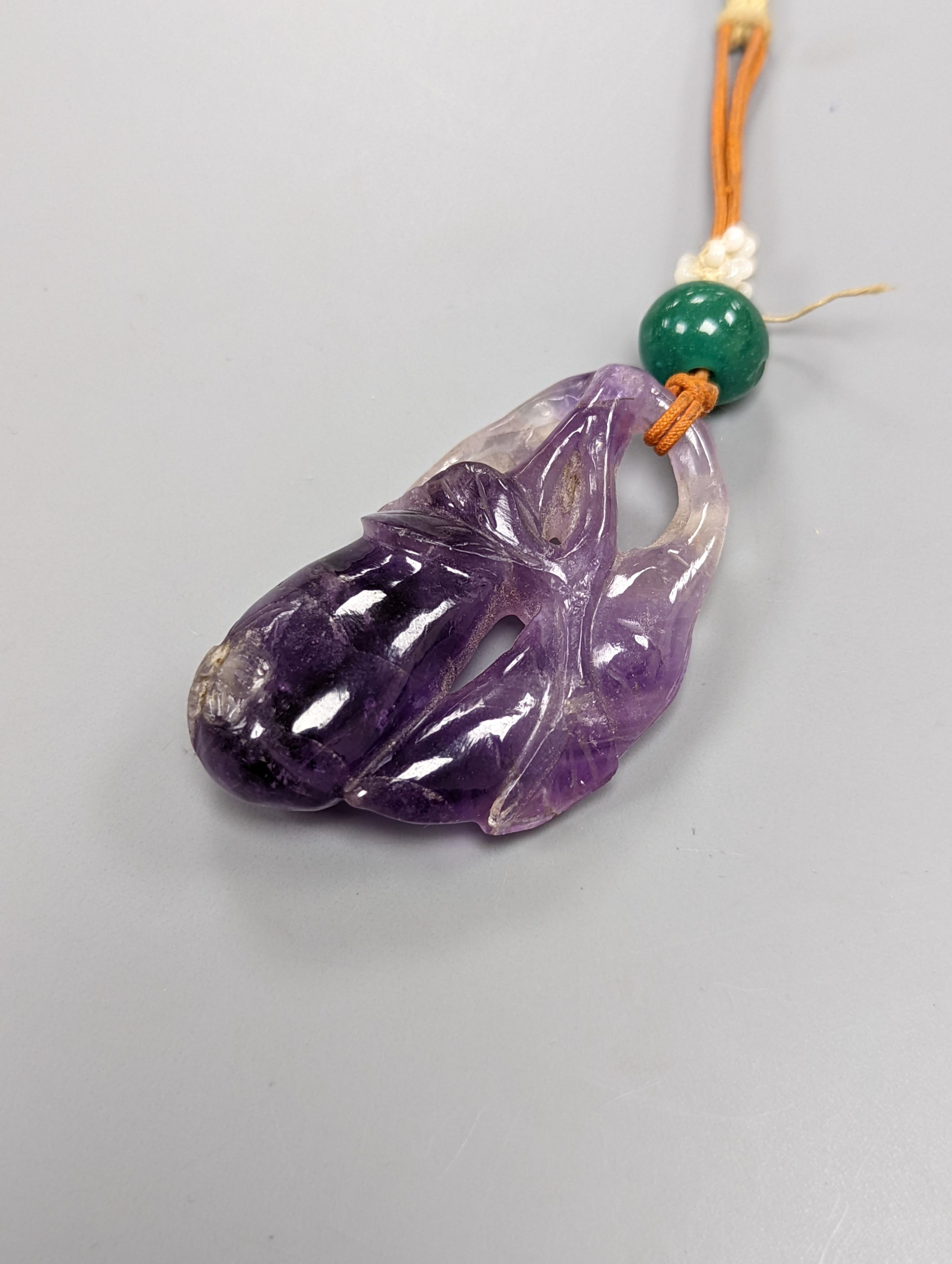 A 19th century Chinese carved amethyst pendant, 5cm on an ornate cord